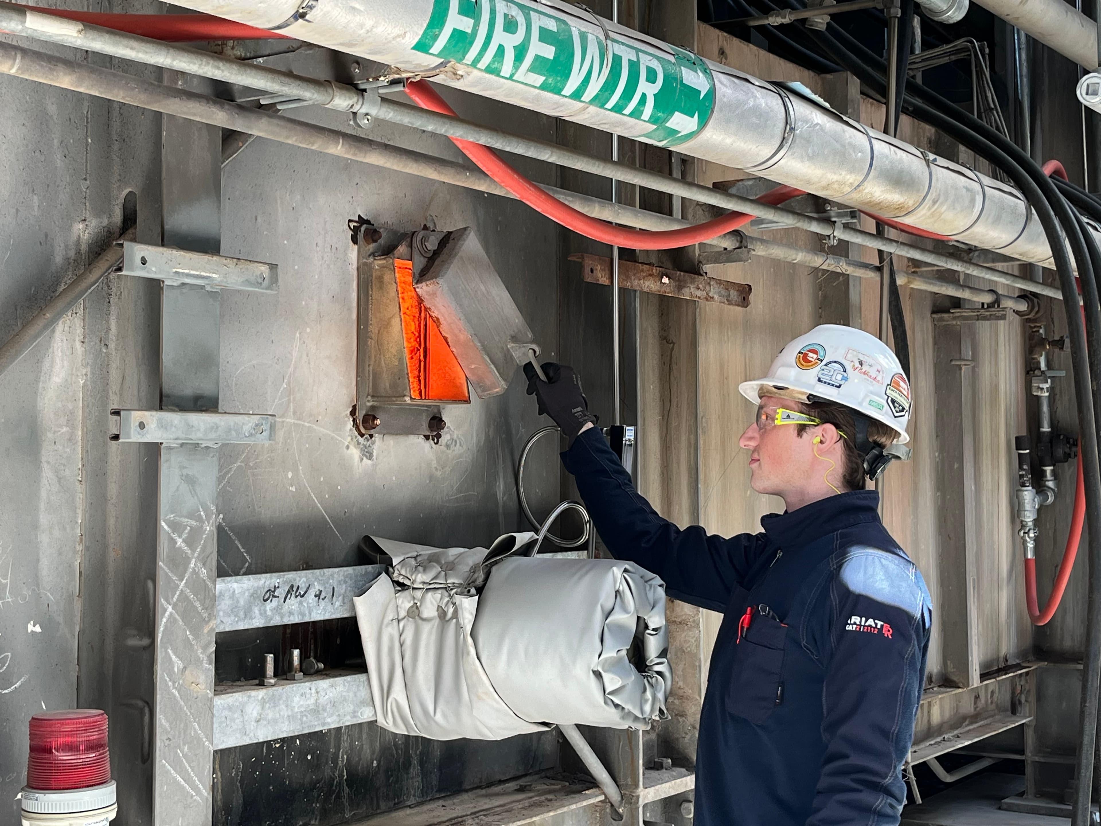 Man in hard hat and safety glasses opening a cover